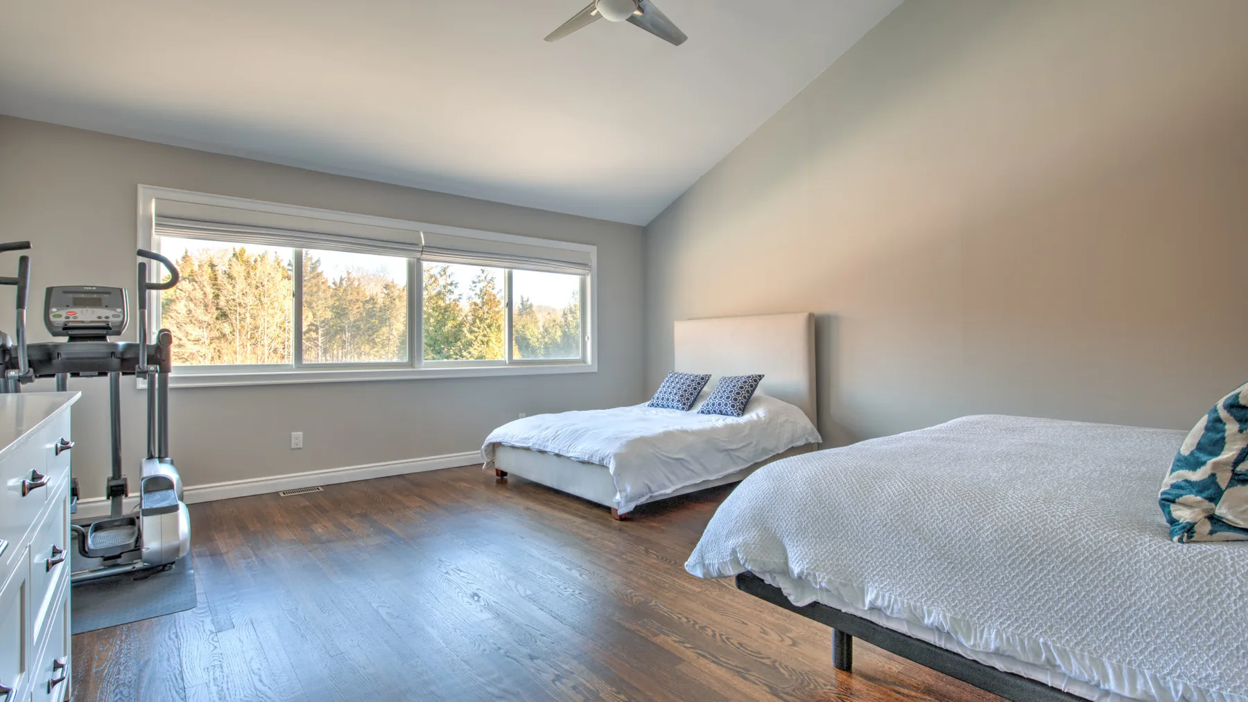 Un dormitorio con dos camas y una ventana con vista a árboles.