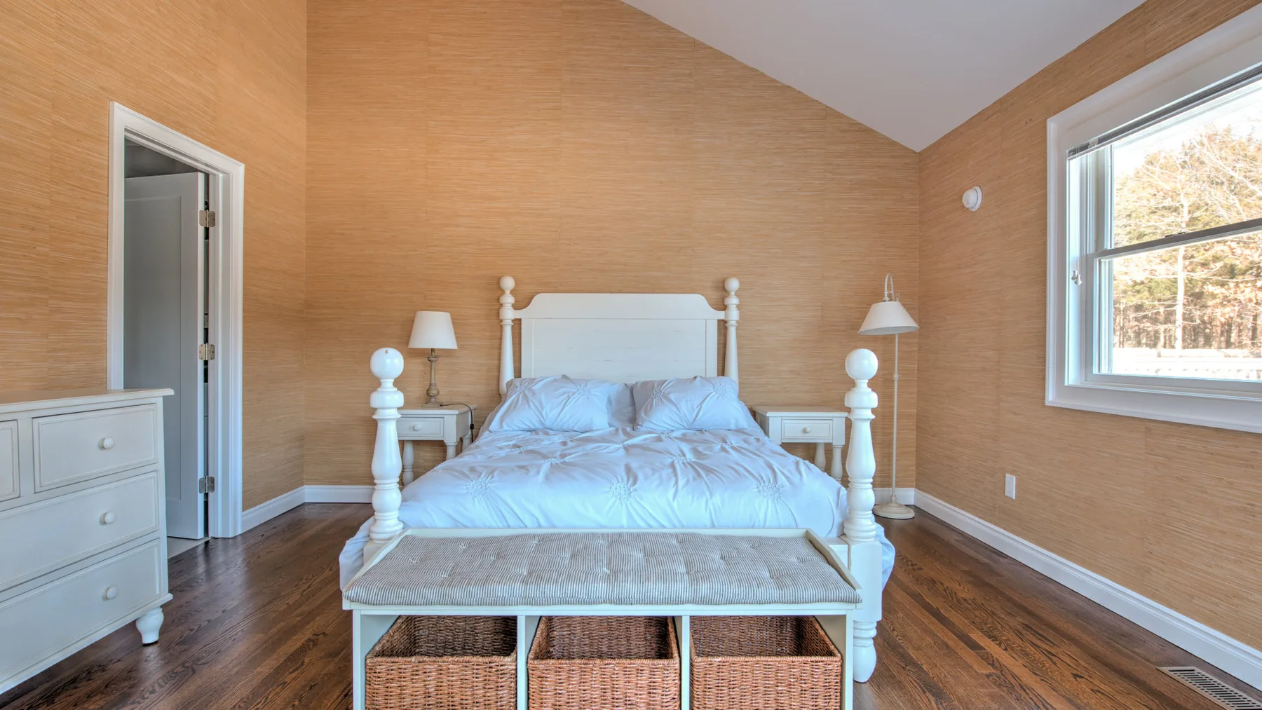 Dormitorio con una cama blanca, mesas de noche y una ventana.