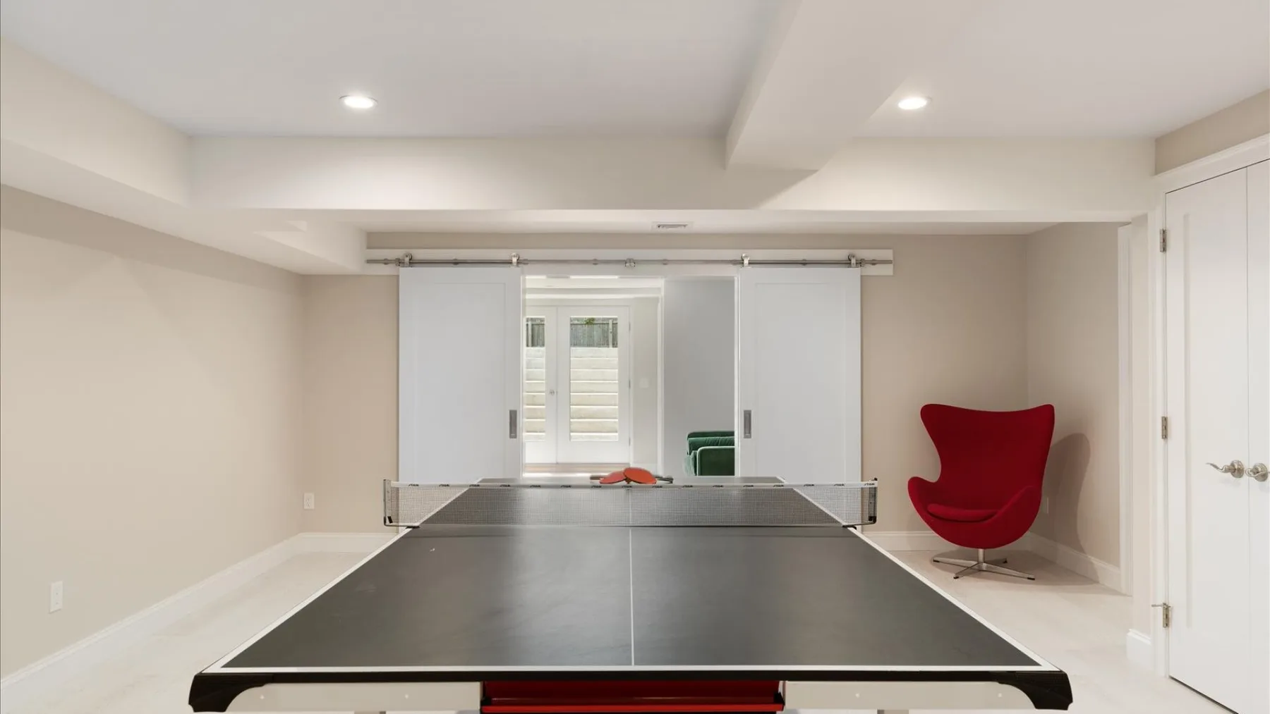 Una sala de recreación con una mesa de ping-pong y un sillón rojo.