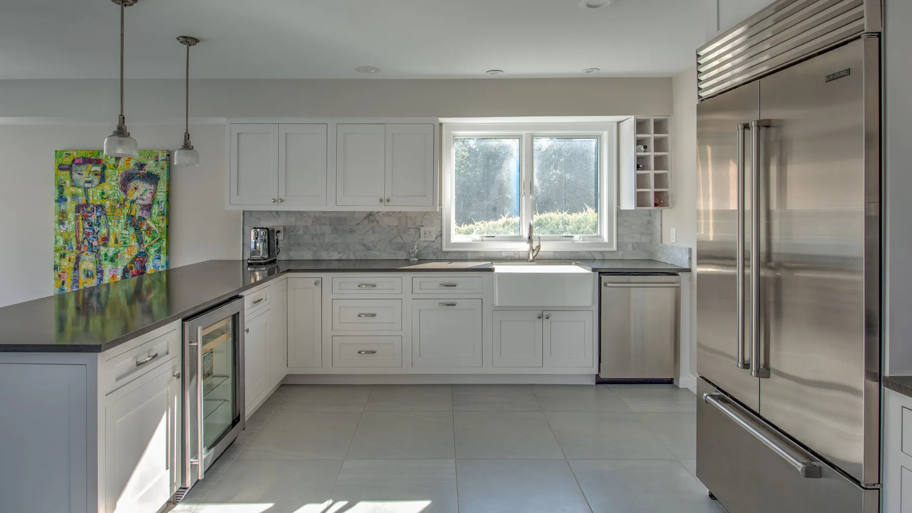 Una cocina luminosa con armarios blancos, una encimera y una ventana sobre el fregadero.