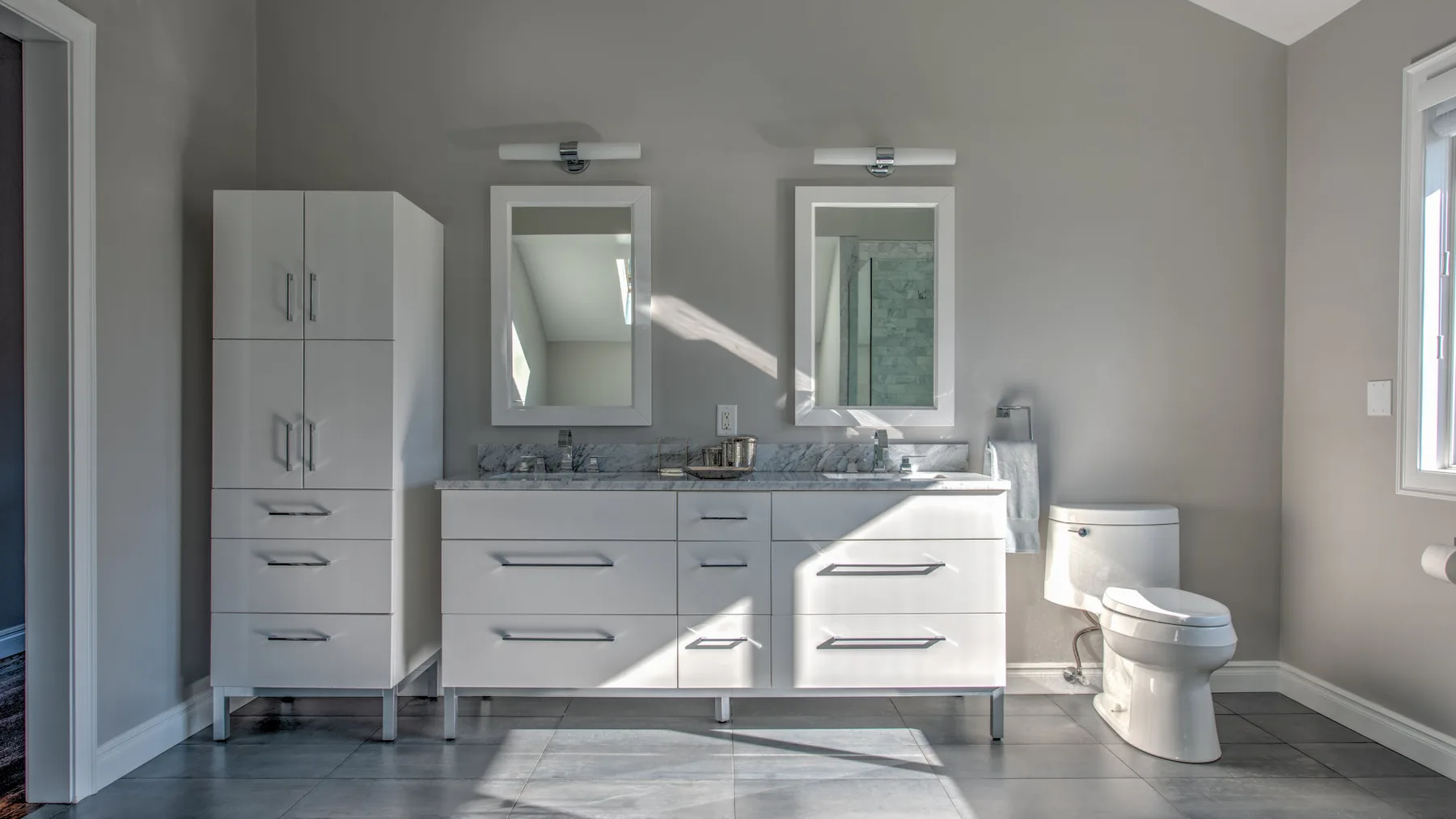 Un baño con lavabo doble, espejos e inodoro.