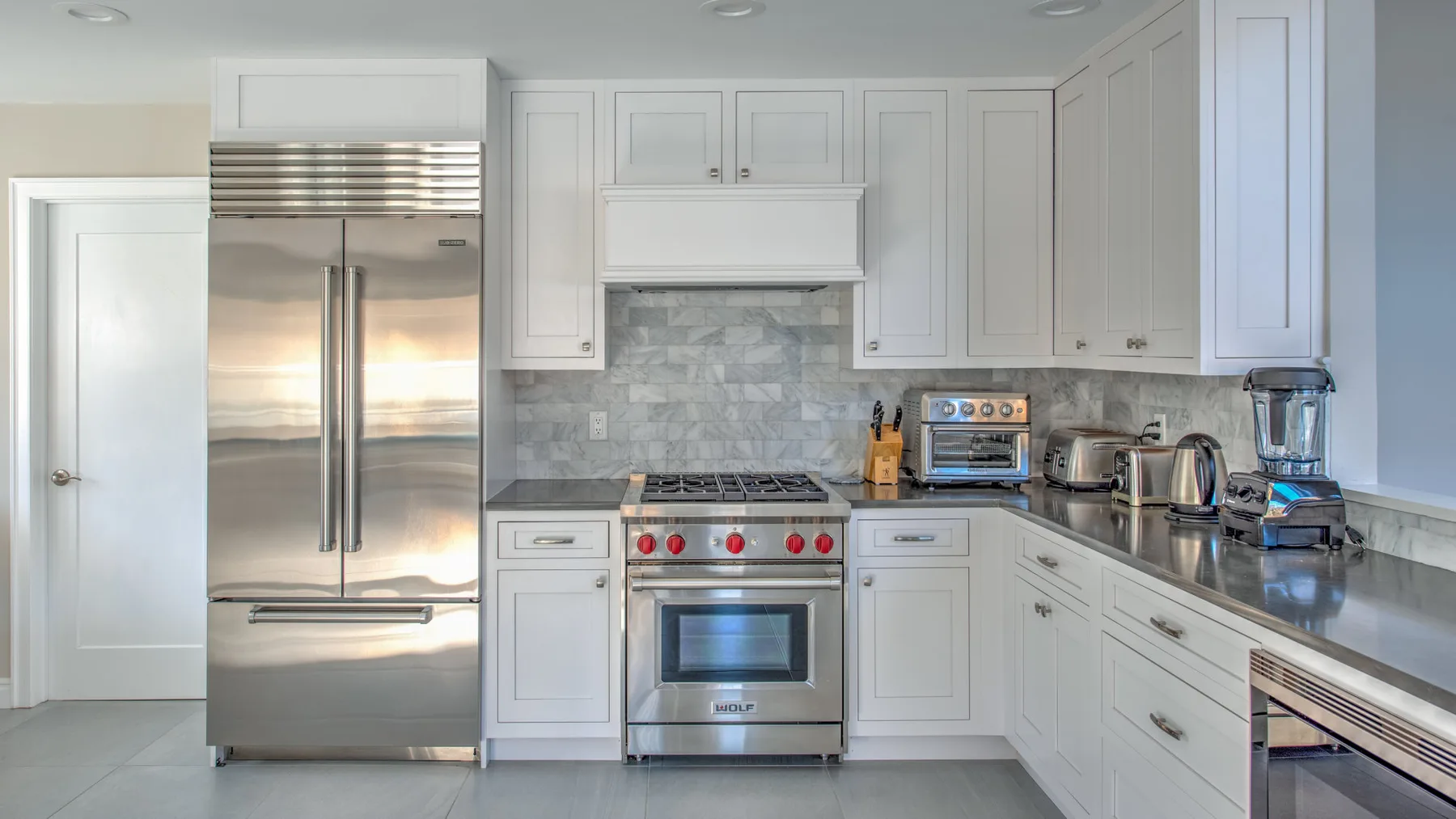 Una cocina luminosa con armarios blancos y electrodomésticos de acero inoxidable.
