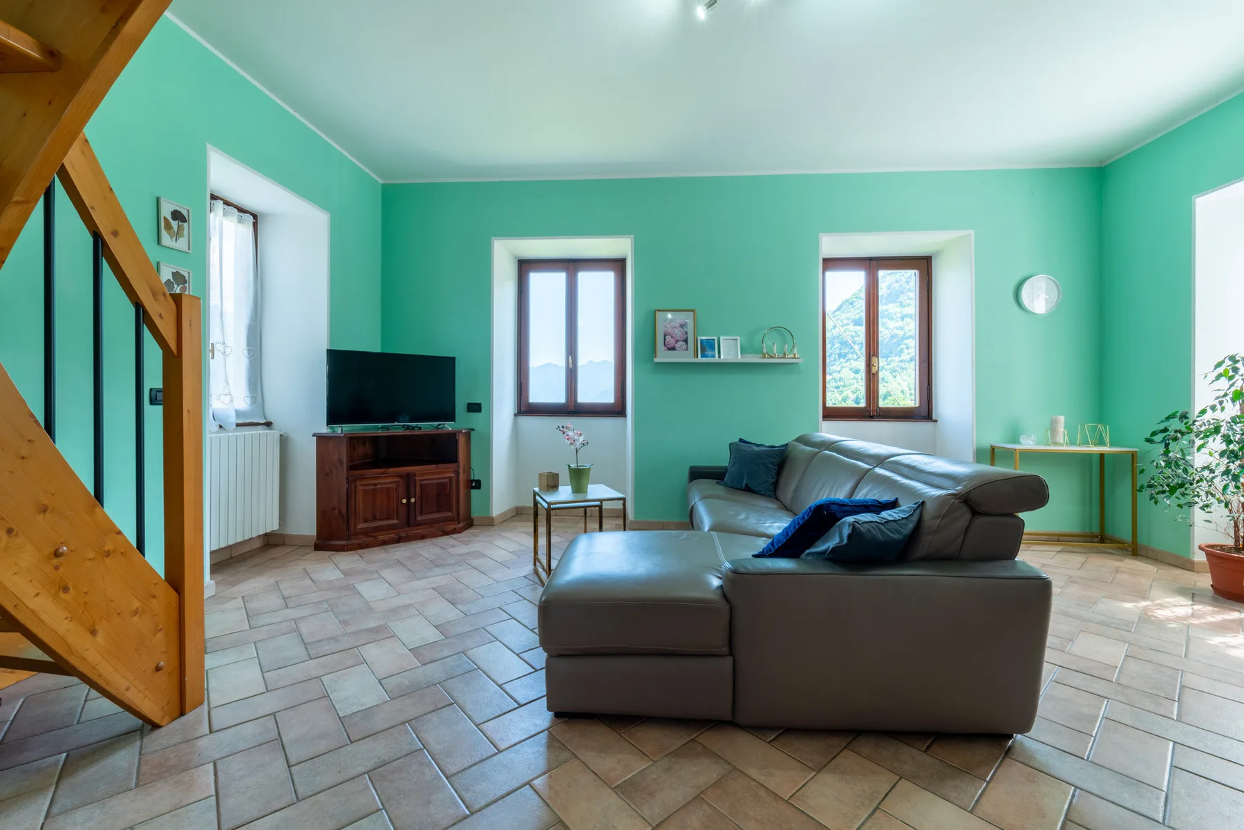 A living room with green walls, tiled flooring, and a seating area.