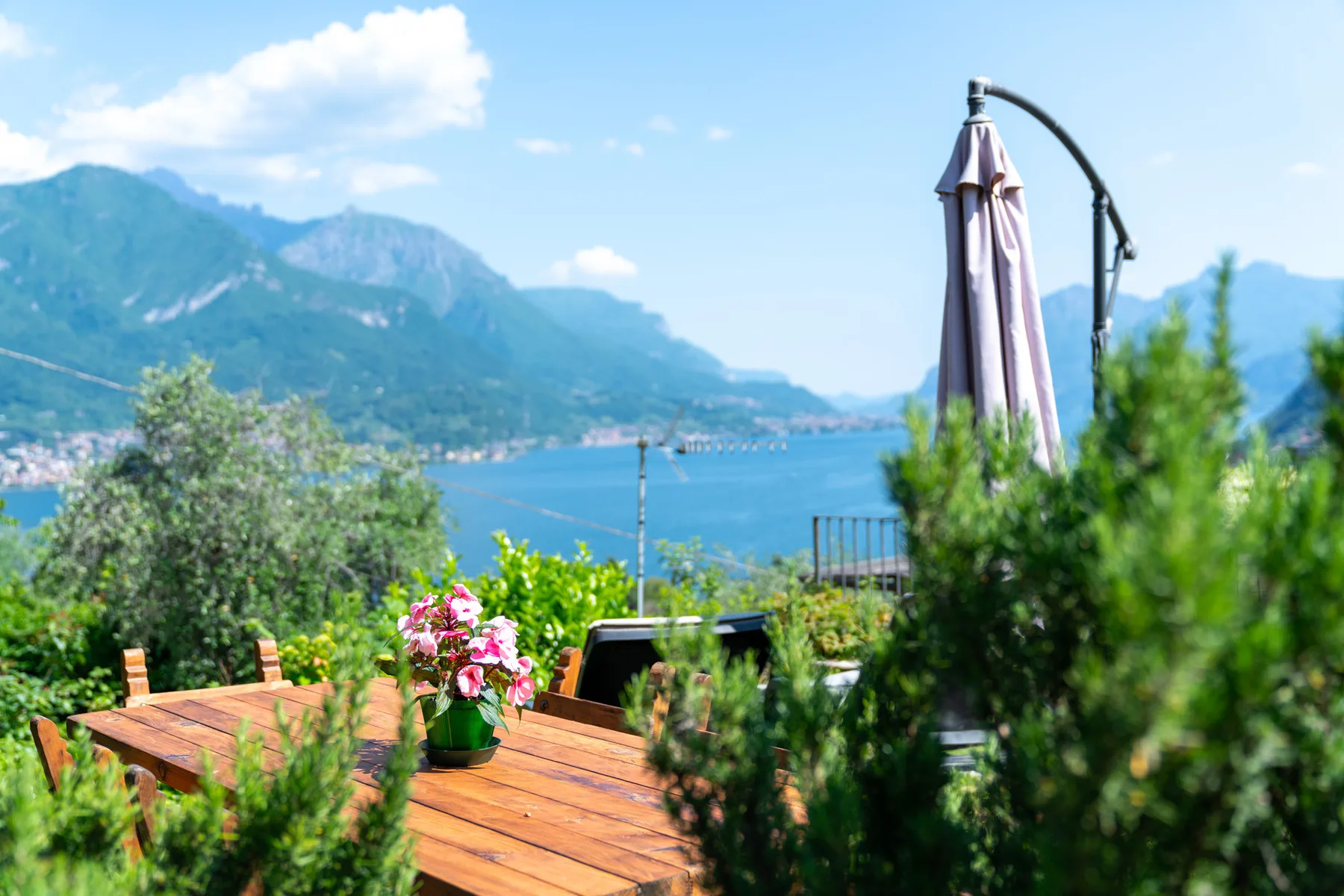 An outdoor wooden dining area overlooks a lake and surrounding mountains.