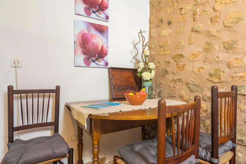 A dining area with a wooden table, chairs, and a stone wall.