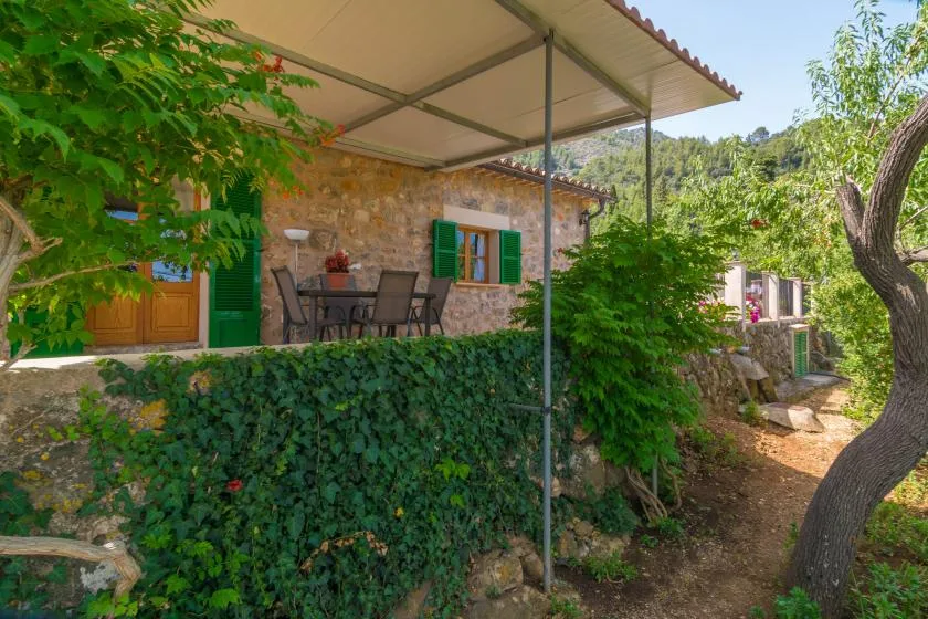 A stone house patio with outdoor seating beneath a covered awning.