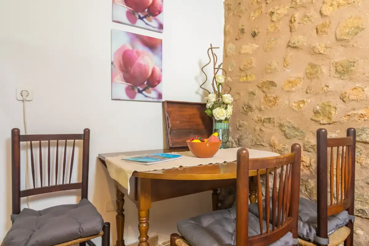 A dining area with wooden seating, a table, and a stone wall.