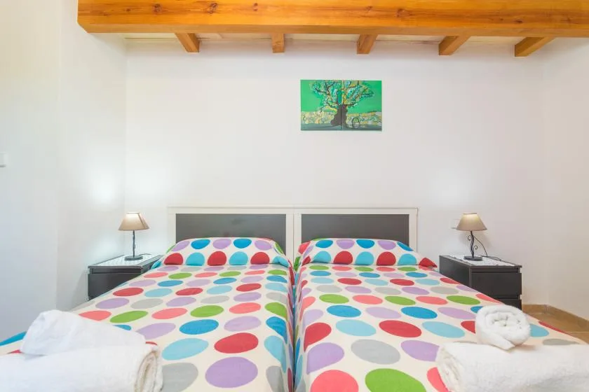 A bedroom with two beds covered in colorful polka-dot bedding.