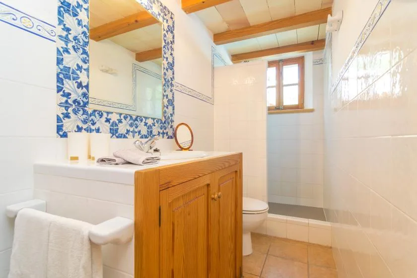 A tiled bathroom with a sink, mirror, and window.