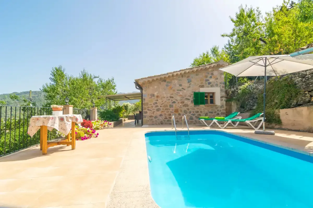 An outdoor swimming pool beside a stone building and patio seating.