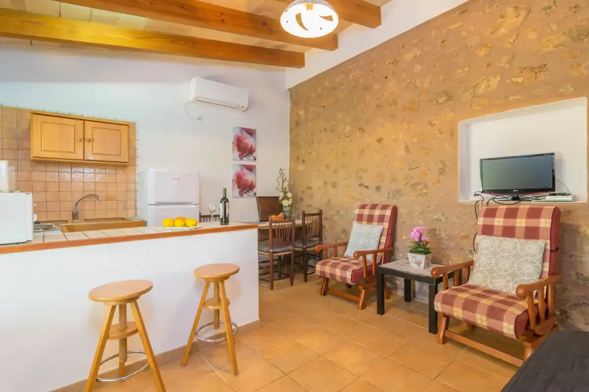 A rustic kitchen and dining area with a counter, wooden stools, and seating.