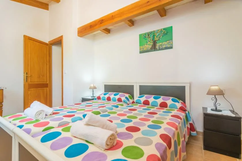 A bedroom with two beds covered in colorful polka-dot bedding.