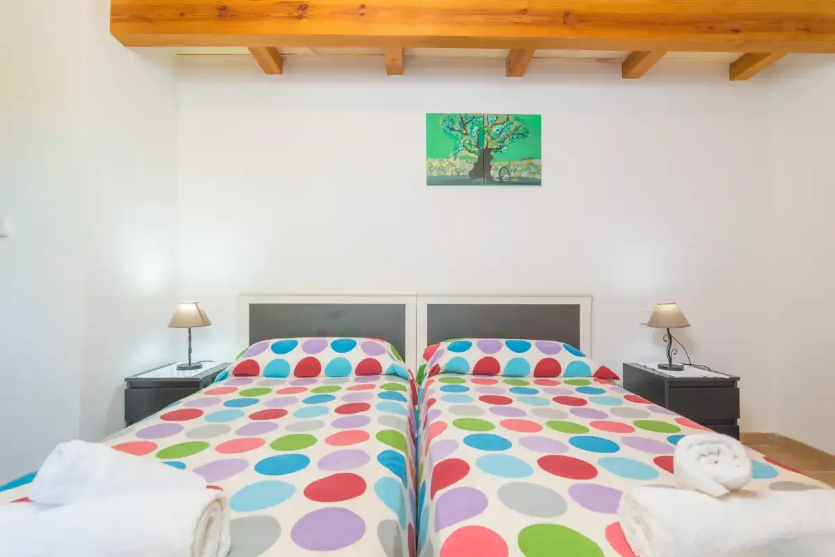 A bedroom with two beds covered in colorful patterned bedding.