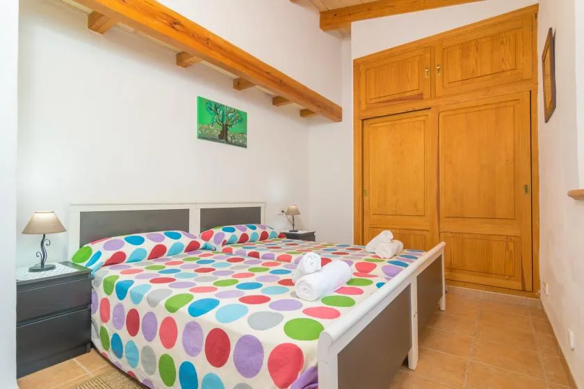 A bedroom with two beds covered in colorful polka-dot bedding.