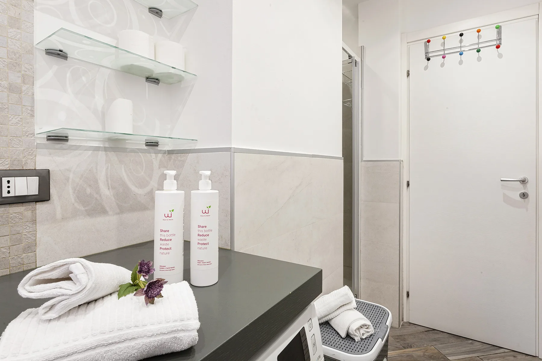 A bathroom counter with folded towels and toiletries beside a closed door.