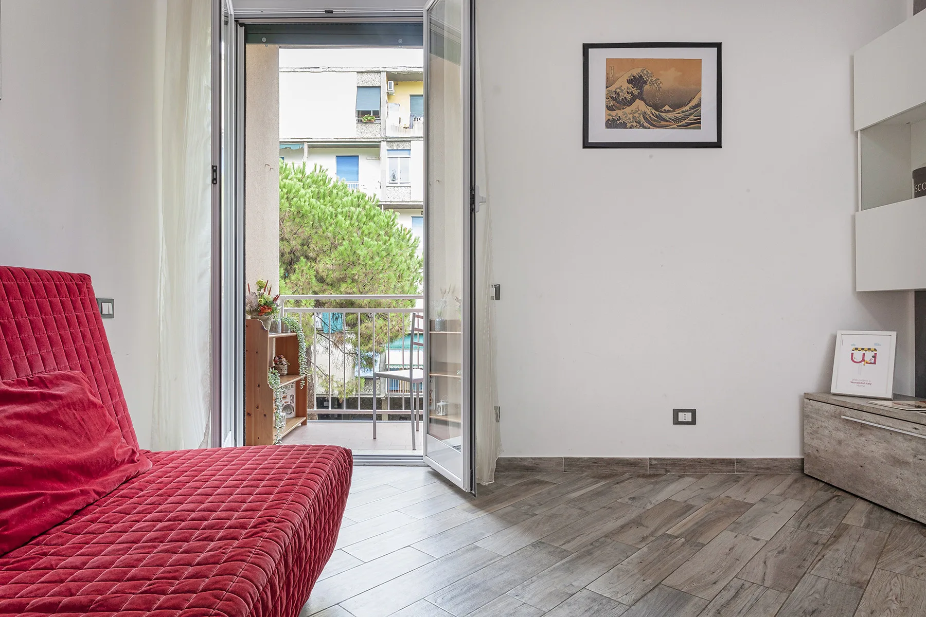 A bright room with red seating and an open door leading to a balcony.