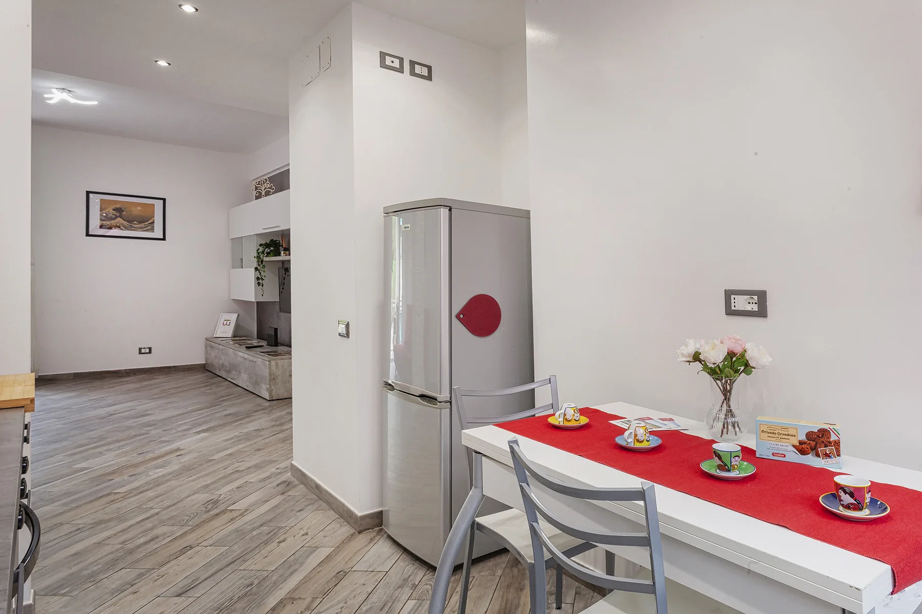 A dining area with a table set with dishes beside a refrigerator.