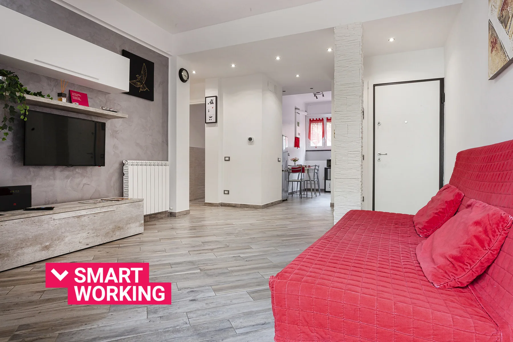 A bright living room with red seating and a television mounted on the wall.