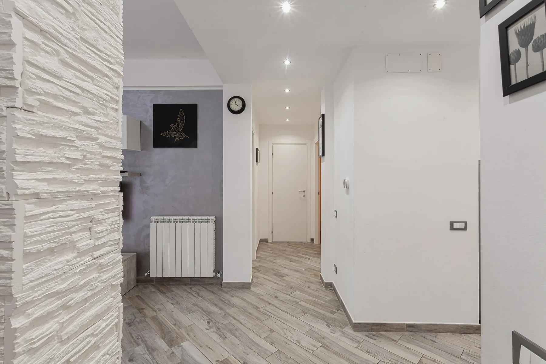 A bright interior hallway with recessed ceiling lights and a closed door.