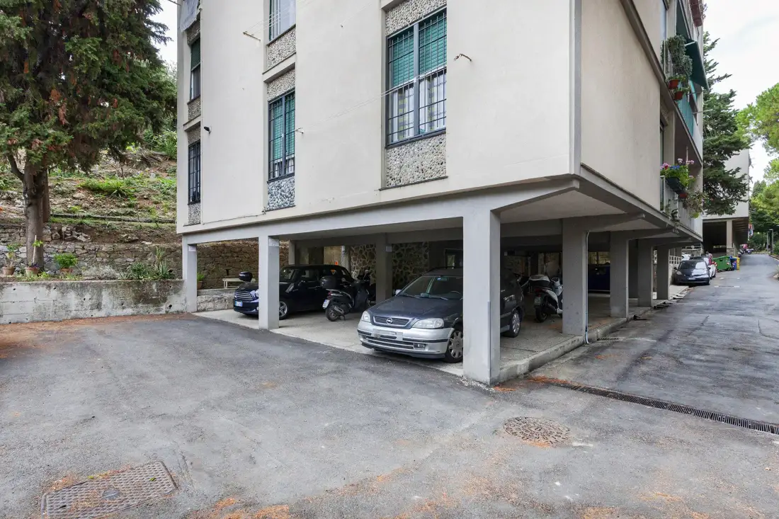 A multi-story building stands above an open ground-level parking area.