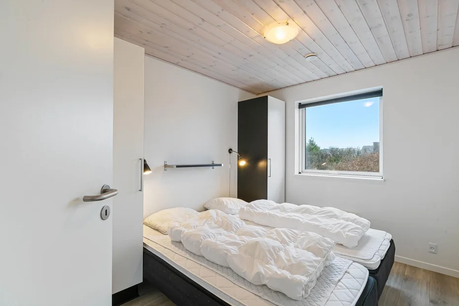Un dormitorio con una cama vestida con ropa de cama blanca y una ventana.