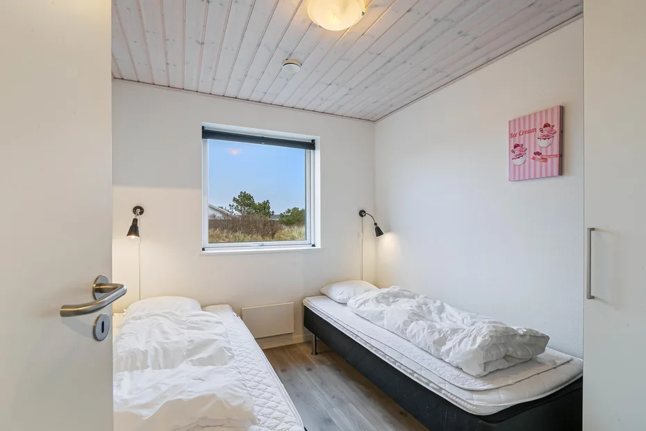 Un dormitorio con dos camas y una ventana con vista a la vegetación.