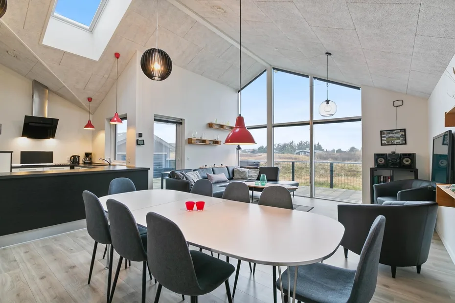 Una luminosa sala-comedor de planta abierta tiene grandes ventanales y una cocina.