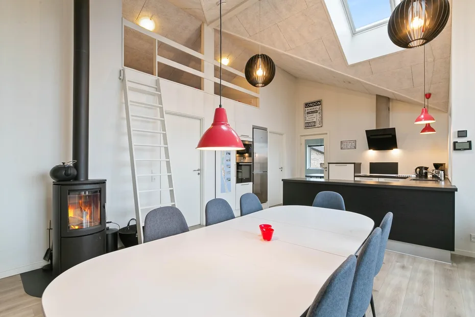 Un comedor luminoso con una mesa larga y una cocina compacta al fondo.