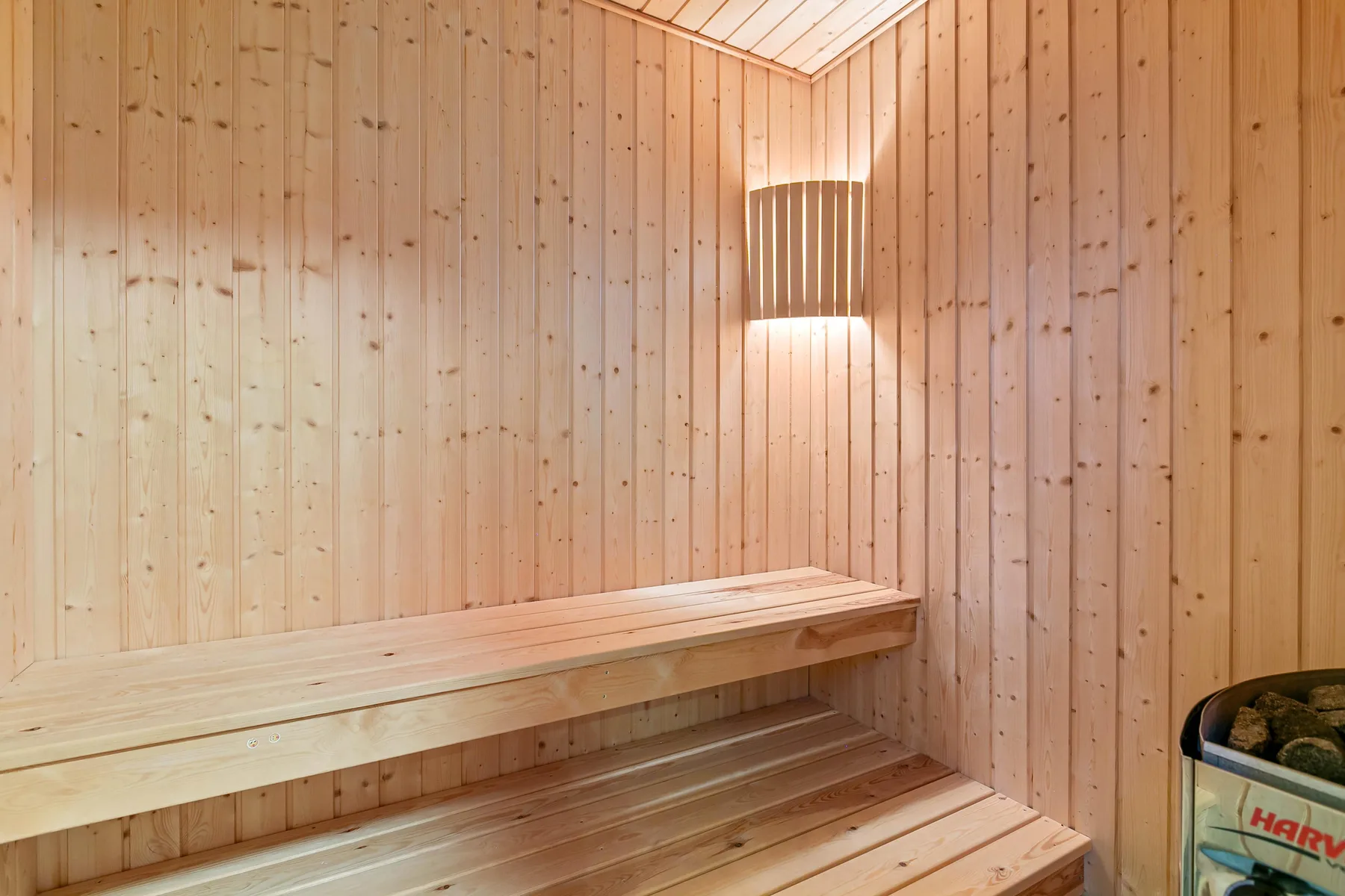 Una sauna revestida de madera, con asientos escalonados y una luz de pared.