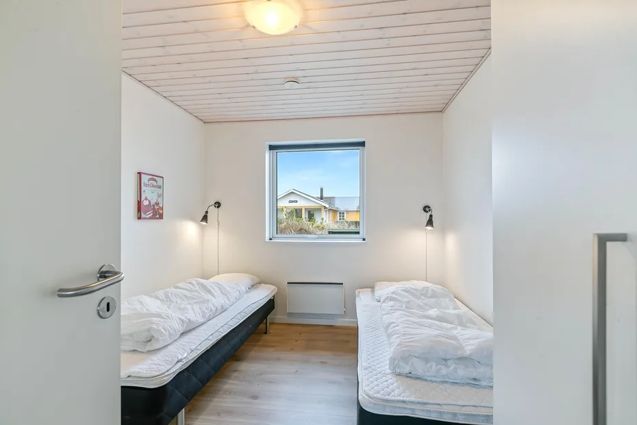 Un dormitorio luminoso con dos camas individuales y una ventana.