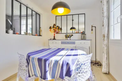 A dining area with a table covered in a blue-and-white striped cloth beneath a pendant light.