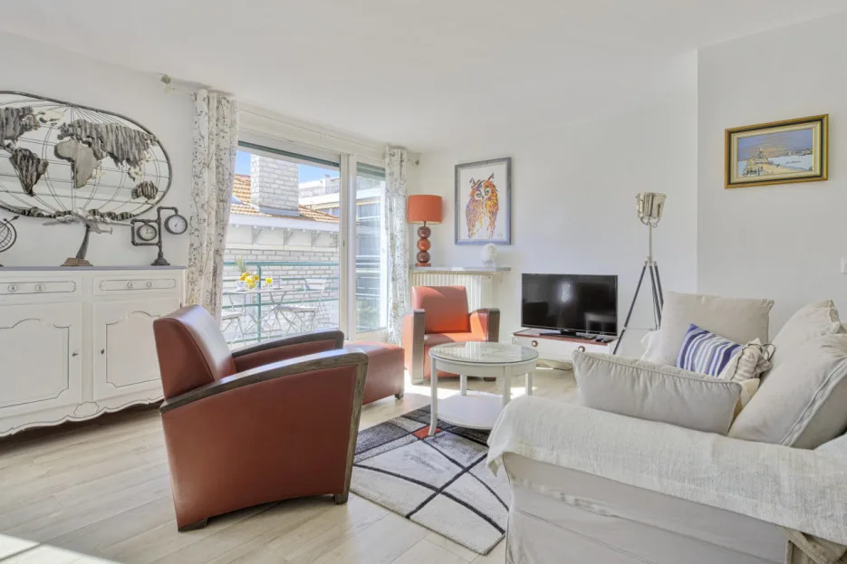 A bright living room with seating arranged around a coffee table and television.