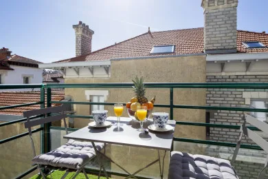 A small rooftop terrace has a table set with drinks and a pineapple.