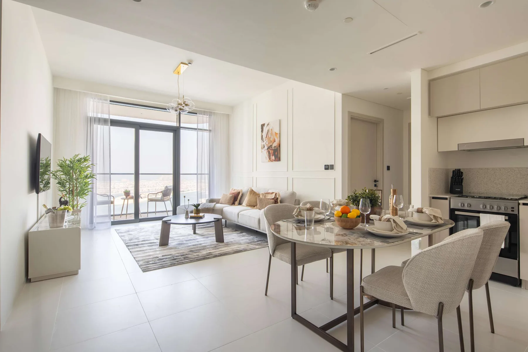 Una luminosa sala-comedor de concepto abierto con cocina y grandes ventanales.