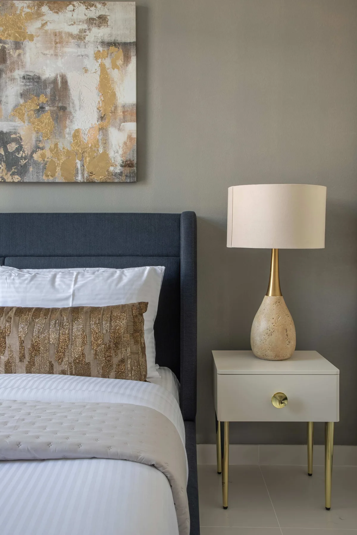 Un dormitorio con una cama tendida y una mesita de noche con una lámpara.