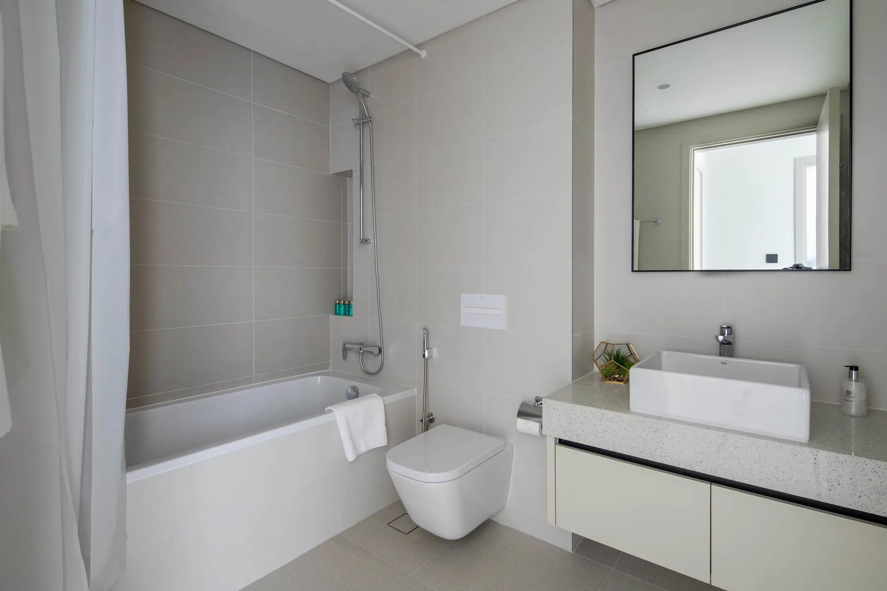 Un baño moderno con bañera, ducha, inodoro y lavabo.