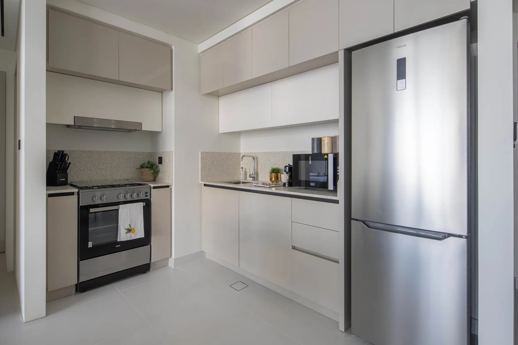Una cocina moderna con gabinetes claros, un refrigerador de acero inoxidable y un horno.