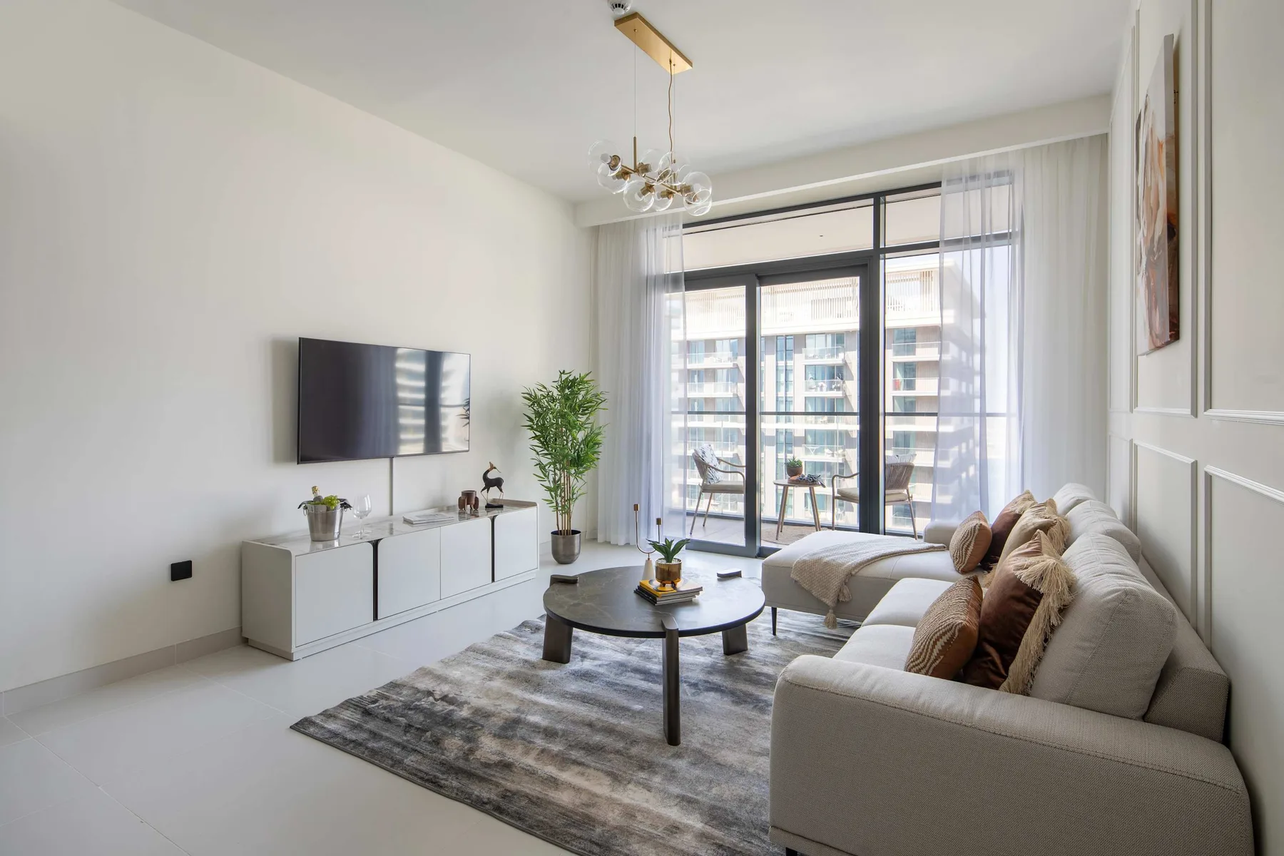 Una luminosa sala de estar con zona de descanso, mesa de centro y ventanales.