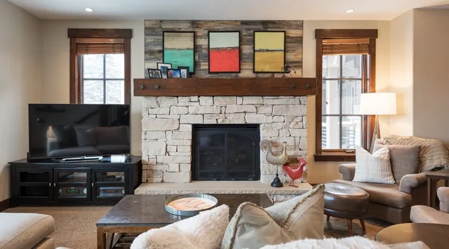 Una sala de estar con chimenea de piedra, televisor y asientos.