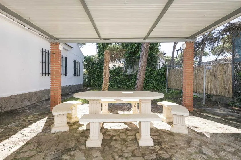 A covered outdoor dining area with a stone table and benches.