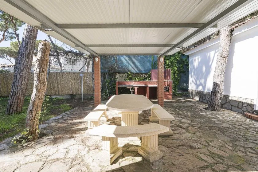 A covered outdoor dining area with a table and built-in benches.