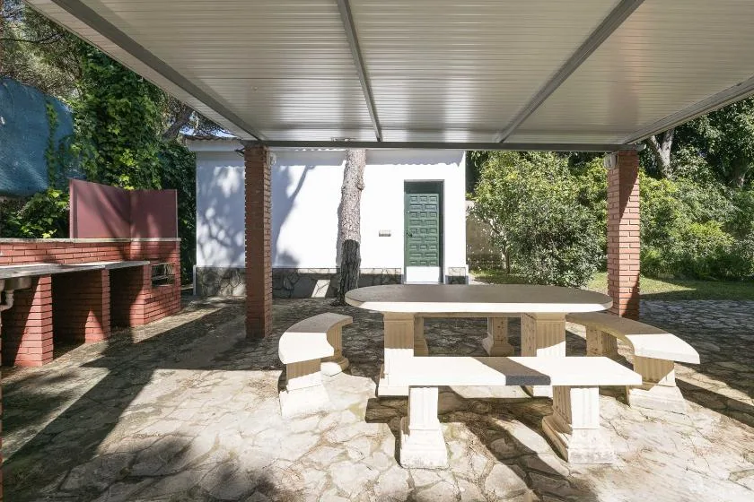 A covered outdoor dining area with a stone table and built-in seating.