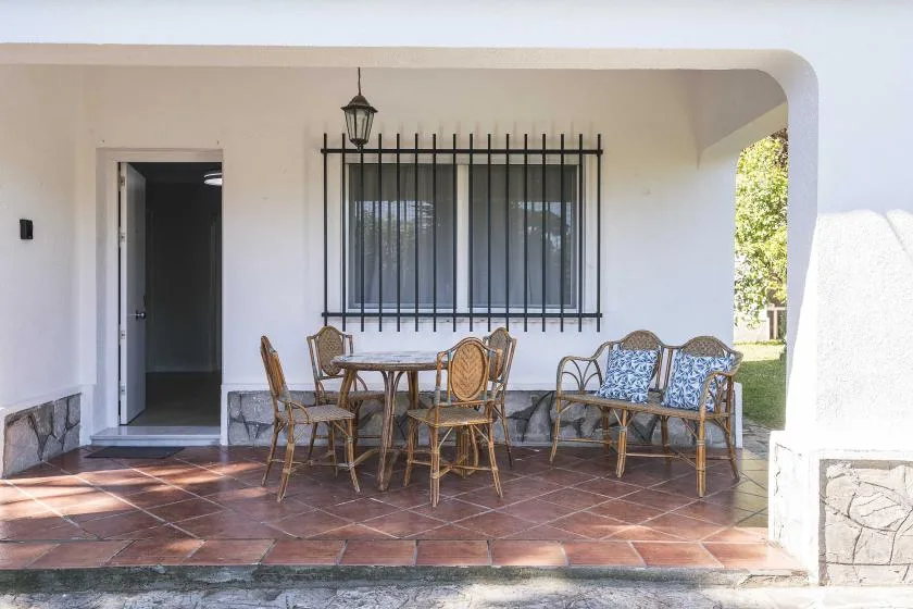 A covered patio with a dining table and outdoor seating beneath a barred window.