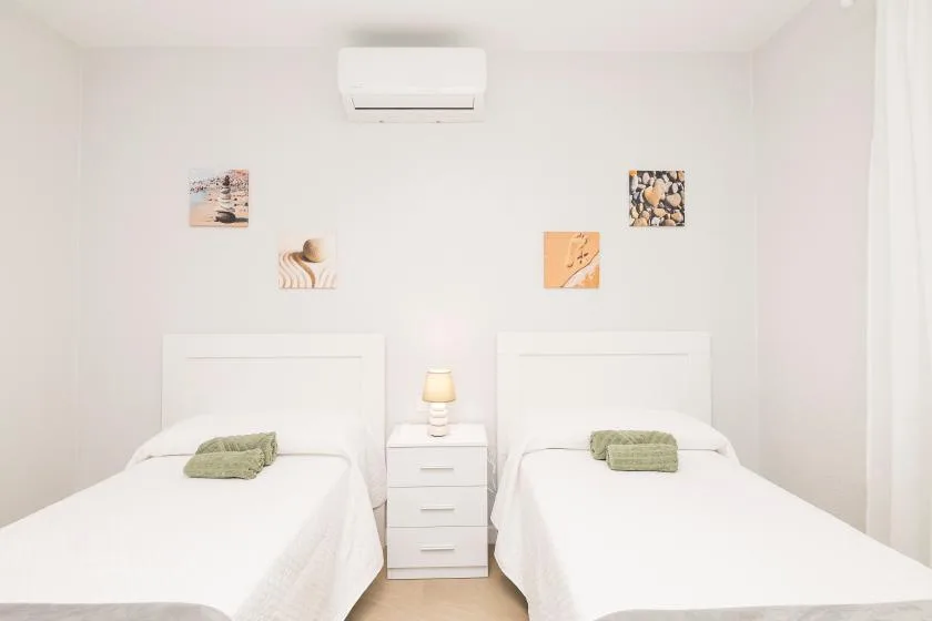 A bright bedroom with two beds and a small bedside table between them.
