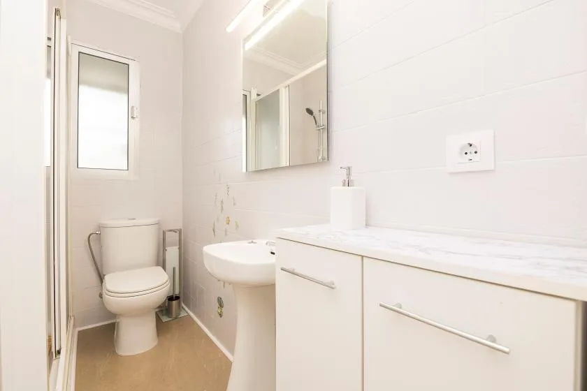 A bright bathroom with a toilet, sink, and vanity.