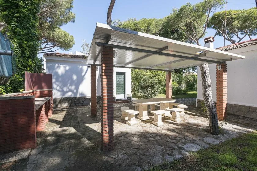 A covered outdoor patio with a picnic table and surrounding trees.