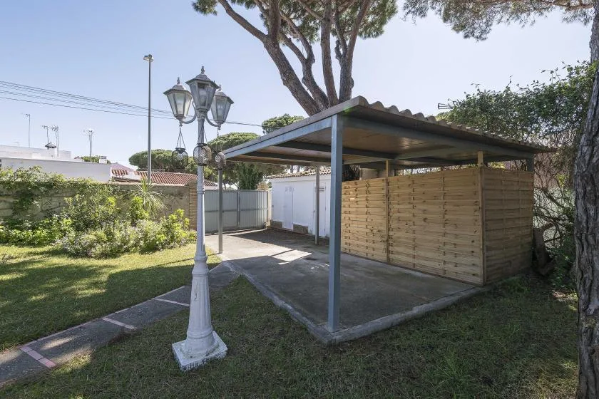 A covered outdoor area with a wooden privacy screen beside a grassy yard.