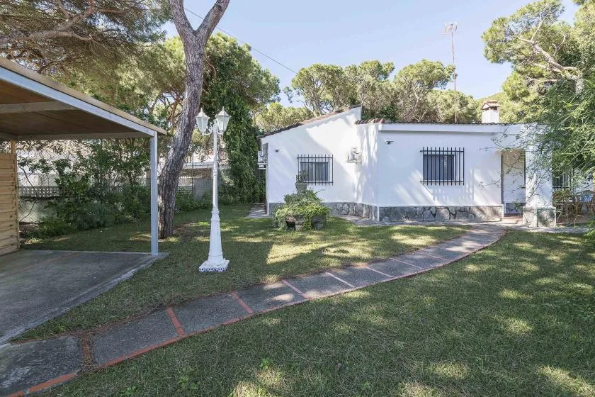 A white building stands beside a grassy yard and a paved walkway.
