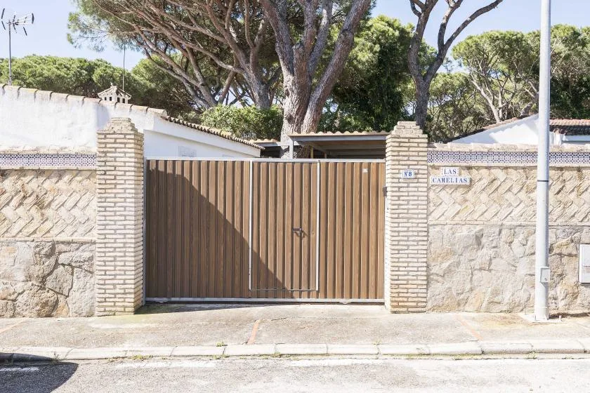 An outdoor entrance with a tall wooden gate between stone walls.