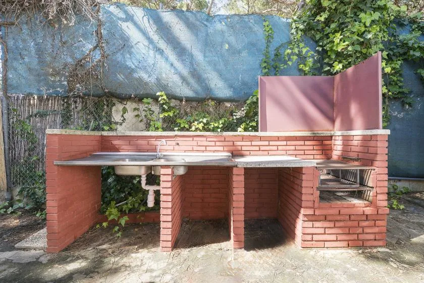 An outdoor brick cooking area with a wide counter and a built-in grill.